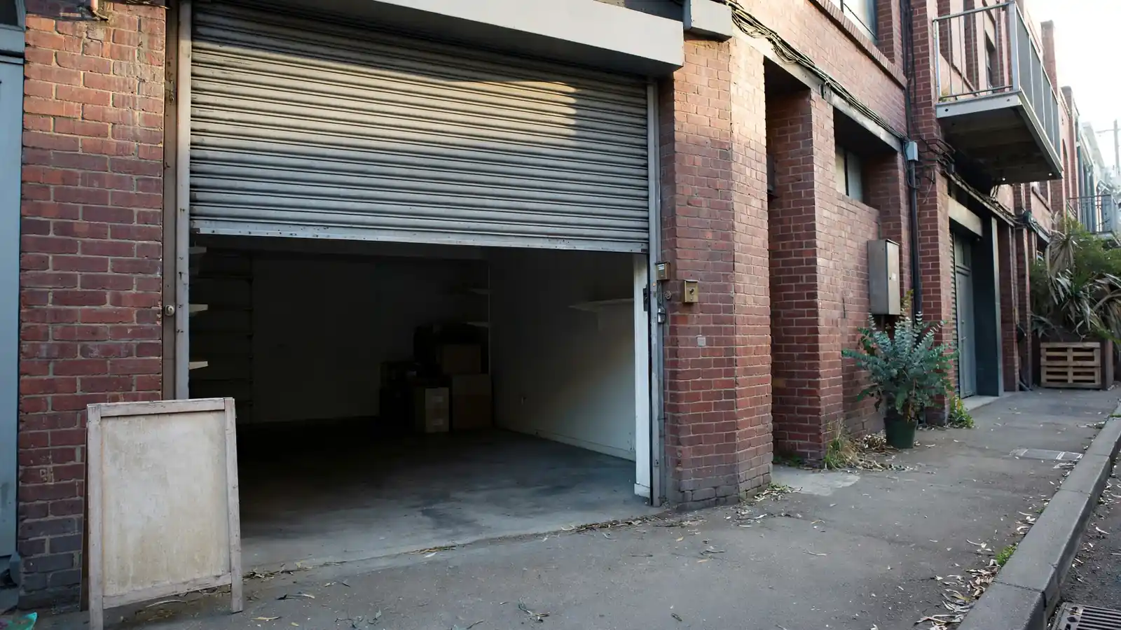 Closed shopfront with half-lowered shutter on quiet Australian laneway